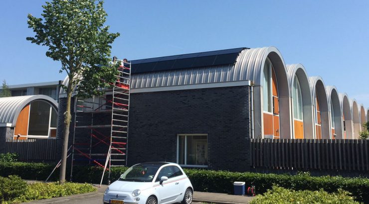 Een huis met zonnepanelen een witte auto